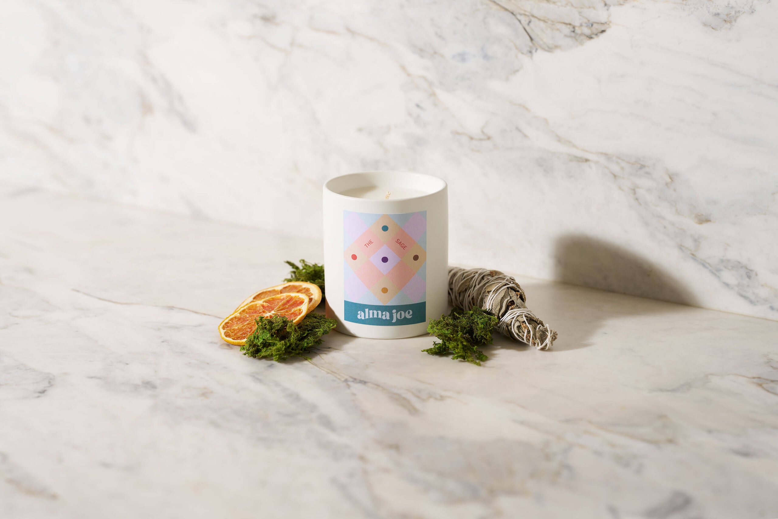 the sage candle sitting next to orange slices and sage